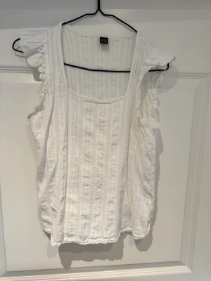 Vit blus med volangärm från SHEIN - Söt vit blus från SHEIN i storlek M. Blusen har volangdetaljer vid ärmhålen och en fyrkantig ringning. Tillverkad i ett lätt och luftigt tyg, perfekt för varmare dagar. Enkel att matcha med både jeans och kjol.