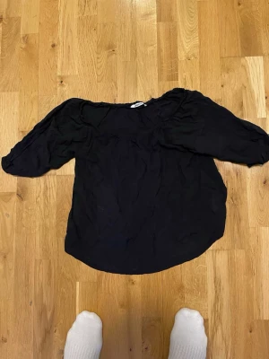 Svart offshoulder blus Gina Tricot stl 34 - Snygg svart offshoulder blus från Gina Tricot i storlek 34. Blusen har en lös passform och trekvartsärmar med lätt puff vid axlarna. Perfekt att styla med jeans eller kjol för en trendig look.