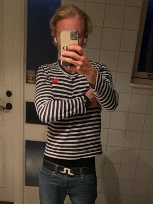 Randig långärmad tröja Comme des Garçons - Säljer en blåvit randig långärmad tröja från Comme des Garçons PLAY med det klassiska röda hjärtat på bröstet. Tröjan har rund halsringning och är i mjukt bomullsmaterial. Perfekt för en stilren och trendig look.