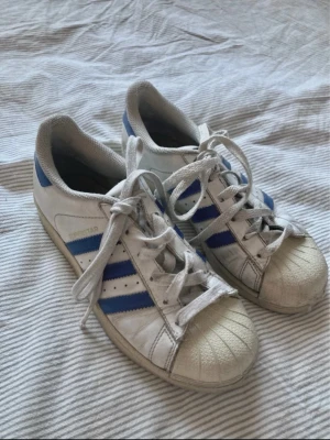 Adidas superstars - Coola superstars med blåa detaljer! Köpta secondhand. Kommer tyvärr inte till användning längre❤️