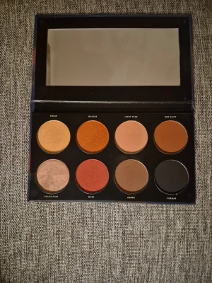 Infinity Deep Palette ögonskugga - Snygg ögonskuggspalett från Linda Hallberg med åtta nyanser i varma och jordiga toner som guld, koppar, röd, brun och svart. Paletten har både matta och skimrande färger och kommer i en stilren ask med spegel i locket. Den är swatchad . En fin palett. 