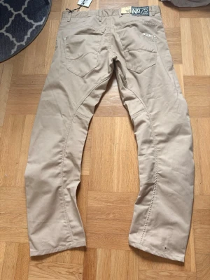 Beiga vintage  chinos från Jack & Jones - Snygga beiga chinos från Jack & Jones med klassisk passform och två bakfickor. Byxorna har en stilren look och är tillverkade i ett mjukt bomullsmaterial som ger en skön känsla. Perfekta för dig som vill ha en clean och enkel stil.
