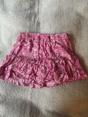 Rosa kjol med shorts Zara - Supersöt kjol från Zara i rosa och vitt med blommigt mönster och volangdetaljer. Kjolen har resår och snörning i midjan och även inbyggda shorts (se andra bild)! Storlek M💝