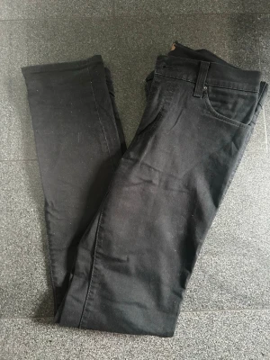 Levi's 510 Super Skinny svarta jeans - Svarta Levi's 510 Super Skinny jeans med klassisk femficksdesign och smal passform hela vägen ner. Jeansen är tillverkade i stretchigt material för extra komfort och sitter tight längs benen. Perfekta för dig som gillar en modern och slimmad look. W32 L32.