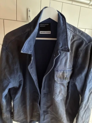 Blå overshirt från ENFANTS RICHES DÉPRIMÉS - Snygg blå overshirt från ERD med klassisk krage och knappstängning framtill. Bröstficka med knappdetalj och raka ärmar. Distressed, men endast använd en hanfull gånger. Cropped/ Boxy fit