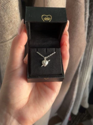 Silverhalsband med hjärthänge Maria Nilsdotter - Säljer ett stilrent silverhalsband från Maria Nilsdotter med ett litet hjärthänge. Kedjan är tunn och smidig, och hänget har en mjuk, organisk form. Perfekt för dig som gillar minimalistiska smycken med en personlig touch.
