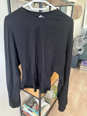 Svart långärmad topp från Nelly - En enkel svart långärmad topp från Nelly med rund halsringning. Tillverkad i mjukt material som känns skönt mot huden. Perfekt att styla med jeans eller kjol för en clean look.