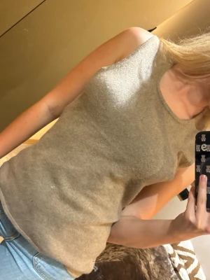 Beige stickad linnetopp (inte fläck på tröja  - Snygg beige stickad linnetopp med rund halsringning. Toppen är ärmlös och har en enkel, stilren design som passar perfekt till jeans eller kjol. Mjuk och skön mot huden, perfekt för varmare dagar. OBS: Ett litet manhål där nere