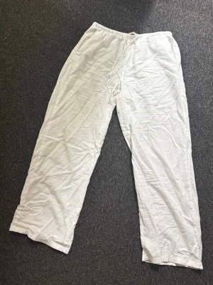 Vita linnebyxor från Gina Tricot - Snygga och luftiga vita linnebyxor från Gina Tricot med resår i midjan. Byxorna har rak passform och är tillverkade i ett tunt och svalt linnematerial, perfekta för varma dagar.