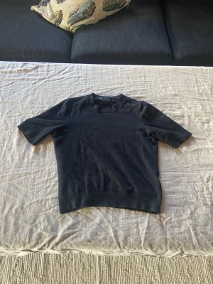 Svart kortärmad topp i bomull - En enkel och stilren svart topp med korta ärmar och rund halsringning. Tillverkad i mjuk bomull som känns skön mot huden. Perfekt att matcha med jeans eller kjol för en clean look.