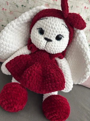 Virkad kanin i röd klänning - Supergullig handgjord mjuk kanin i tjockt, fluffigt garn. Kaninen har stora vita öron, svarta broderad nos, och blå glittriga säkerhetsögon, samt bär en röd klänning och matchande rosett som är avtagbara. Perfekt som present eller dekoration i rummet. 38cm
