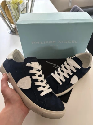 Philippe Model blåa sneakers strl 42 (helt nya)  - Snygga sneakers från Philippe Model i mörkblå mocka med vita detaljer och vita skosnören. Säljer mina skor då dom inte riktigt var som jag tänkt mig och vill nog testa ett par andra skor. Riktigt fina och bra skick inte en ändå skråma. Strl 42