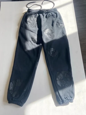 Denim Tears Cotton Wreath-Black Pants - Hej! (Jag vill få bort byxorna så fort som helst för att jag har köpt en större storlek till honom och hann inte returnera dem. Kan säkert gå med på ditt prisförslag).                                                                    Hej, Rasmus här👋. Säljer dessa Denim Tears byxor pågrund av att dem inte används av sonen. Storlek Smal. Perfekt för dig med bra stil. Kolla gärna min profil om hoodie sökes också😁.   Först till kvarn som man säger 👋😁