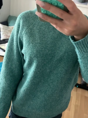 Turkos stickad tröja Weekday - Säljer en turkos stickad tröja från Vero Moda. Tröjan har rund halsringning, långa ärmar och ribbade muddar vid ärmslut och nederkant. Perfekt för dig som gillar en enkel men snygg look. Materialet känns mjukt och skönt mot huden.