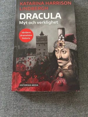 Dracula: Myt och verklighet - En fängslande bok av Katarina Harrison Lindbergh om Dracula, där myt möter verklighet. Omslaget är svart och rött med en illustration av Vlad Tepes och ett slott. Perfekt för dig som gillar historia, vampyrer och dramatiska berättelser.