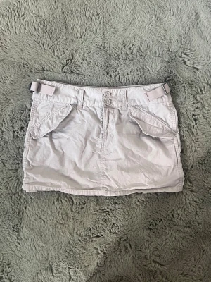Minikjol - Säljer en low waist cargo kjol från h&m. Den är beige och i storlek XS. Kjolen är knappt använd och säljs inte längre. Midjemått: 39 cm, höjden: 30 cm.💗