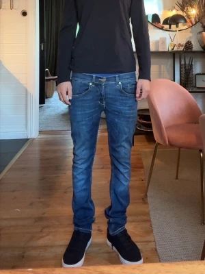 Blåa dondups slim fit jeans  - Säljer ett par blå slim fit jeans  . Jeansen har låg midja, fem fickor och silverfärgade nitar. Perfekta för en avslappnad och trendig look.
