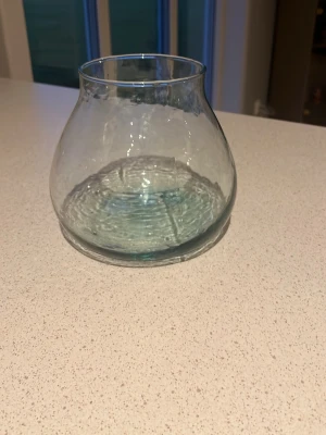 Rund glasvas i transparent glas - Säljer en rundad glasvas i transparent glas med bred botten och smalare öppning. Perfekt för snittblommor eller som dekoration på bordet. Enkel och stilren design som passar i de flesta hem.