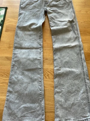 Gråa bootcut jeans från 157 - Säljer ett par gråa jeans från 157 med bootcut passform och klassisk femficksdesign. Jeansen har knappgylf och är tillverkade i ett mjukt denimtyg som ger en avslappnad look. Perfekta för dig som gillar en enkel och stilren stil.