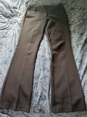 Svarta kostymbyxor  - Säljer ett par svarta kostymbyxor med klassiskt pressveck och utsvängda ben. Byxorna är lågmidjade och bootcut nertill. Byxorna har hällor för skärp och fickor fram. Perfekta för en clean och stilren look. Köpte för 500kr. De är i modellen Vera. 