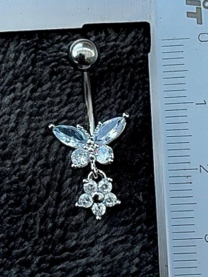 NY oanvänd Navelpiercing med hänge | Kirurgiskt stål | Fjäril, blomma och vita stenar  - 💕30% Bundle-rabatt vid köp av minst 2 artiklar. ⭐️NY oanvänd piercing i kirurgiskt stål; rostfritt och säkert för läkta piercingar.                               📏MÅTT ⭕️Stavens längd: 10mm ⭕️Stavens tjocklek: 1,6mm ⭕️Smyckets totala längd: 25mm                                                                         🤍Färger: Silver och vit                                                            💌Skickas spårbart via Plick SafePay.