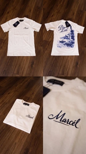Leon marcel - Vit t-shirt från Leon  Marcél med ett stort blått tryck på ryggen vinflaska, glas och havsmotiv med texten Dolce Lith. Liten logga på bröstet fram. Klassisk passform, sitter snyggt till jeans eller shorts. 
