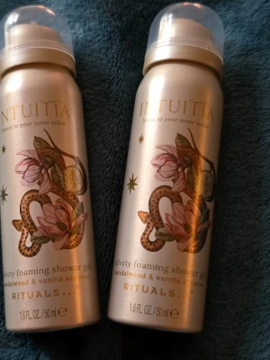 Rituals Intuita duschgel 50 ml ( 2 st) - Två flaskor Rituals Intuita velvety foaming shower gel med doft av sandelträ och vanilj. Flaskorna är guldiga med blommigt och ormmönster, och har en praktisk plastkork. Perfekt för dig som gillar lyxiga duschprodukter med unik design.