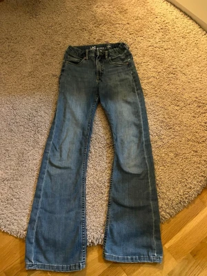 Blå jeans från LAB Industries - Säljer ett par klassiska blå jeans från LAB Industries med snygga kontrastsömmar och femficksmodell. Jeansen är tillverkade i mer hållbart denim och har en normal passform. Perfekta för dig som gillar en enkel och tidlös stil. Storlek 146 men kan passa till om man är längre än det också.