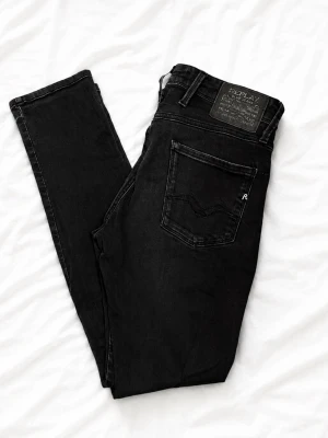 Svarta skinny jeans från Replay - Snygga svarta skinny jeans från Replay med klassisk femficksmodell och diskret logga på bakfickan. Jeansen har smal passform och är tillverkade i stretchigt material för extra komfort. Perfekta till en trendig streetwear-look. OBS Byxorna har krympt lite i tvätten. Så det kanske är närmare 30-30