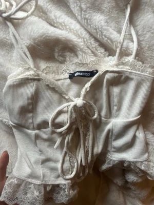 Vit söt topp  - Supersöt vit topp från Gina Tricot, spetsdetaljer och knyt framtill. Toppen har smala axelband och volangkant nedtill i spets. Såå fin speciellt på våren/ sommaren