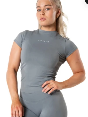 Relode - Aura Seamless T-shirt Stl S - Snyggt grått träningsset från Relode med tight passform. Setet består av en kortärmad topp och matchande tights, båda i stretchigt och mjukt material som andas. Perfekt för gymmet eller annan träning. Diskret logga på bröstet och bak på tightsen.