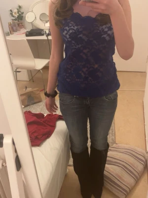 Blå spetslinnetopp med scallopkant - Snygg blå linnetopp i spets med scallopkant upptill. Toppen är ärmlös och har en figurnära passform som framhäver siluetten. Perfekt att styla med jeans eller kjol för en trendig look. Har ett litet hål i, men går att sy!💞