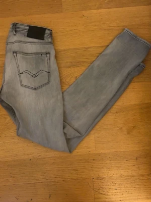 Ljusblå slim fit jeans - Säljer ett par ljusblå slim fit jeans med klassisk femficksdesign och snygga detaljer på bakfickan. Jeansen har en något tvättad look och smal passform som sitter tajt längs benen. Perfekta för en trendig och avslappnad stil.