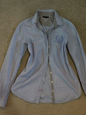 Vintage Tommy hilfiger shorta - Snygg ljusblå skjorta från Tommy Hilfiger med broderad logga på bröstet. Mycket fint skick💕