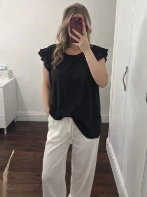 Svart topp med volangärmar från MyWear Women, strlk XL - Säljer en stilren svart topp från MyWear Women i storlek XL köpt secondhand (i samma skick) och har aldrig använts, enbart tvättad en gång. Toppen har vackra volangdetaljer på axlarna som ger ett lyxigt och trendigt uttryck, perfekt både till vardag och fest! FÖRST TILL KVARN!