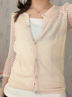 Kofta med små blommor - Söt ljusrosa kofta med blommiga knappar framtill och hålmönstrade partier på ärmar och axlar. Koftan är så snygg men har för många klädesplagg. 😢