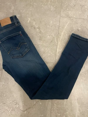 Mörkblå Replay Hyperflex jeans - Säljer ett par mörkblå jeans från Replay, modell Hyperflex. Jeansen har klassisk femficksdesign, smal passform och snygga kontrastsömmar. Materialet är stretchigt för extra komfort och passform. Perfekta för dig som gillar stilrena och bekväma jeans. Skick 9/10. Passar dig som är ungefär 160-165