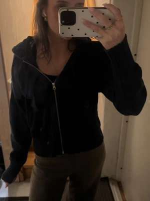 Mörkblå hoodie med dragkedja - Mysig mörkblå hoodie med dragkedja framtill och huva. Tröjan har ribbade muddar och midja, samt en avslappnad passform. Perfekt för en chill och stilren look. Materialet ser ut att vara stickat och ger en skön känsla.