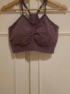 Lila sport-bh med smala axelband - Snygg lila sport-bh med smala, korsade axelband och lätt rynkning framtill. Tillverkad i stretchigt funktionsmaterial som passar perfekt till träning eller yoga.