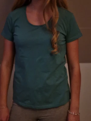 Turkos basic t-shirt i bomull - Enkel turkos t-shirt med rund hals och korta ärmar. Modellen är klassisk och passar perfekt till jeans eller shorts. Tillverkad i mjuk bomull för en skön känsla hela dagen. Aldrig använd.
