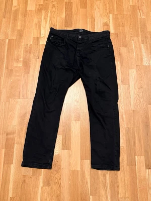 Jeans från CROPP - Säljer ett par svarta jeans från CROPP med rak passform och klassisk femficksdesign. Jeansen har knappgylf och diskret logga bak på linningen. Materialet är mjukt och stretchigt för extra komfort. Väldigt bra kvalitet. Är i storlek W38 L34. 200kr, skriv vid funderingar:)