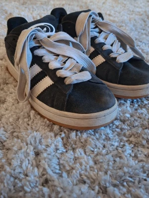 Svarta Adidas sneakers med vita ränder - Slitna bak i hälen på insidan men det är inget som känns när man har på sig dom (se bild)💕Annars mycket fina!