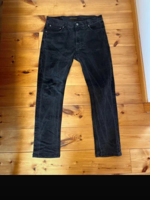 Svarta jeans från Nudie Jeans, modell: Lean Dean  - Säljer ett par svarta jeans från Nudie Jeans med klassisk femficksmodell och raka ben. Jeansen har en diskret logga på bakfickan och är tillverkade i ett mjukt denimtyg. Perfekta för dig som gillar en clean och stilren look.