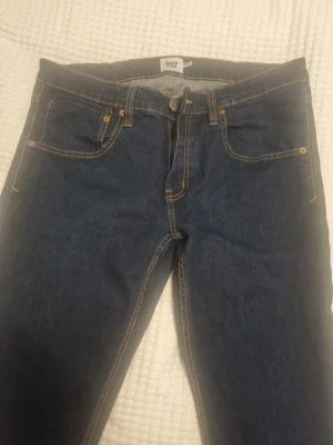 Mörkblå jeans från 157, storlek XL - Säljer ett par klassiska mörkblå jeans från Lager 157 i storlek XL, tror det motsvarar 32 32 när jag jämför med andra från samma märke. Jeansen har fem fickor, raka ben och kontrastsömmar i gult. Tillverkade i slitstarkt denimtyg som passar perfekt till en avslappnad stil.