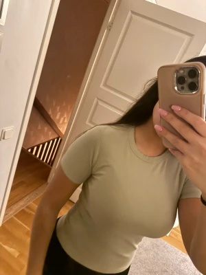 Ljusbeige ribbad kortärmad topp - Snygg ljusgrön  ribbad topp med rund hals och korta ärmar. Figurnära passform som passar perfekt till både jeans och kjol. Enkel och stilren design som är lätt att matcha.