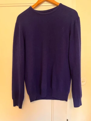 Blå cashmere tröja unisex - Säljer en stilren blå stickad tröja i 100% kashmir. Tröjan har rund halsringning, långa ärmar och ribbade muddar vid ärmslut och nederkant. Perfekt för dig som gillar mjuka och lyxiga material.