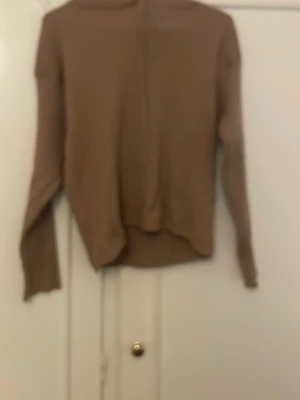 Beige ribbstickad tröja - Säljer en beige ribbstickad tröja med lång ärm och rund hals. Tröjan har en enkel och stilren design med mjukt material och diskreta sömmar. Perfekt för lager på lager och passar till det mesta i garderoben.