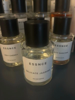 ESSNCE Delicate Jasmine parfym - Minimalistisk parfymflaska från ESSNCE med doften Delicate Jasmine. Flaskan är genomskinlig med svart cylinderformad kork och vit etikett med svart text. Modern och stilren design som passar perfekt på parfymhyllan.