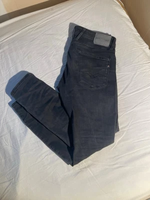 Mörkgrå jeans från Replay - Snygga mörkgrå jeans från Replay med klassisk femficksdesign och diskreta slitningar. Jeansen har raka ben och är tillverkade i mjukt denimtyg med stretch för extra komfort. Perfekta för dig som gillar en stilren och modern look. Kom gärna med frågor!!!!