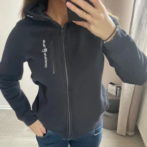 Svart hoodie från sail racing  - Snygg svart hoodie från Sail Racing med dragkedja framtill och en bröstficka med zip. I barn storlek 150 men passar även mig som är 160. Nypris 999kr. I fint skick! 